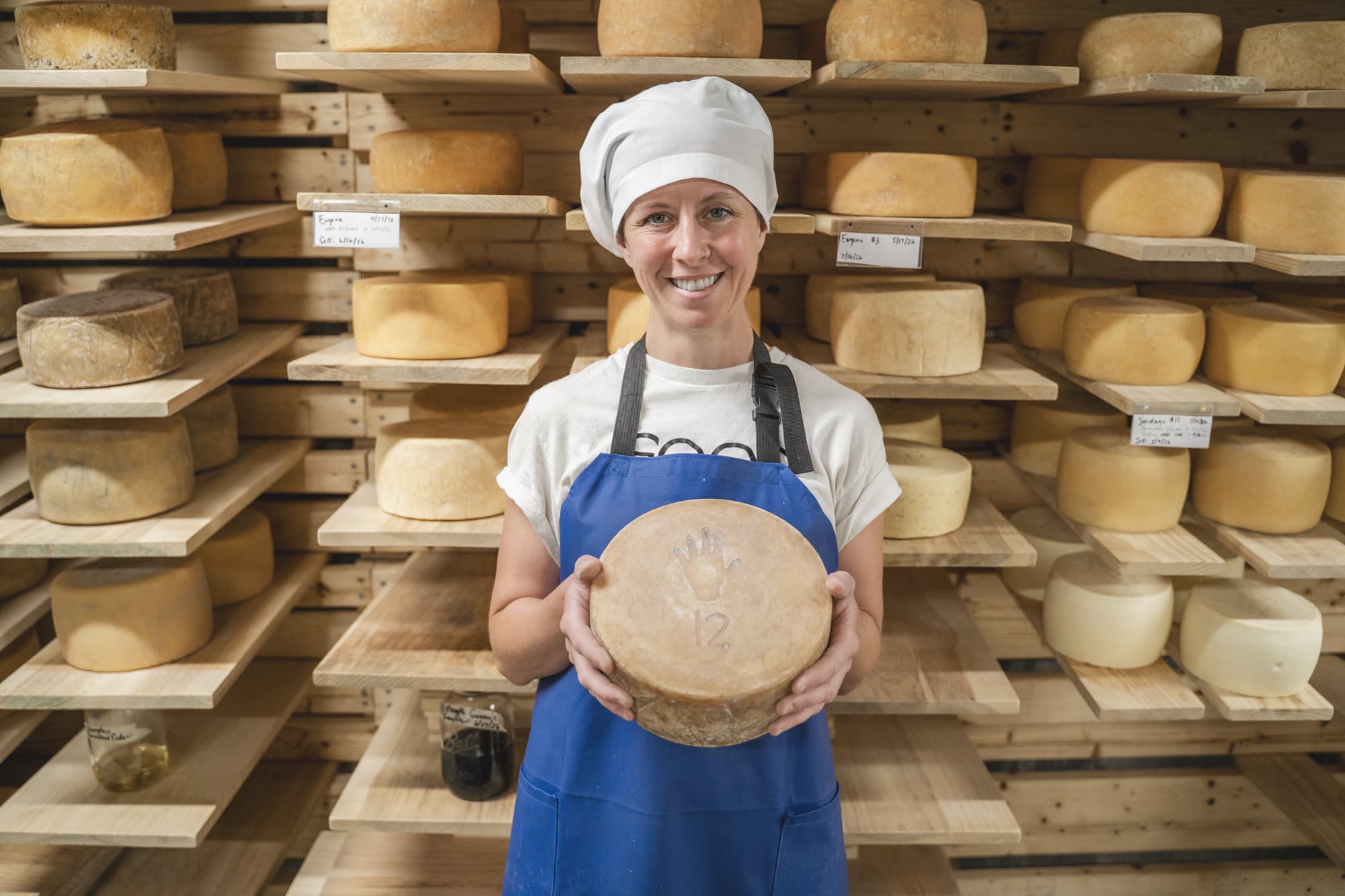 Liz holding a wheel of cheese in the aging cave